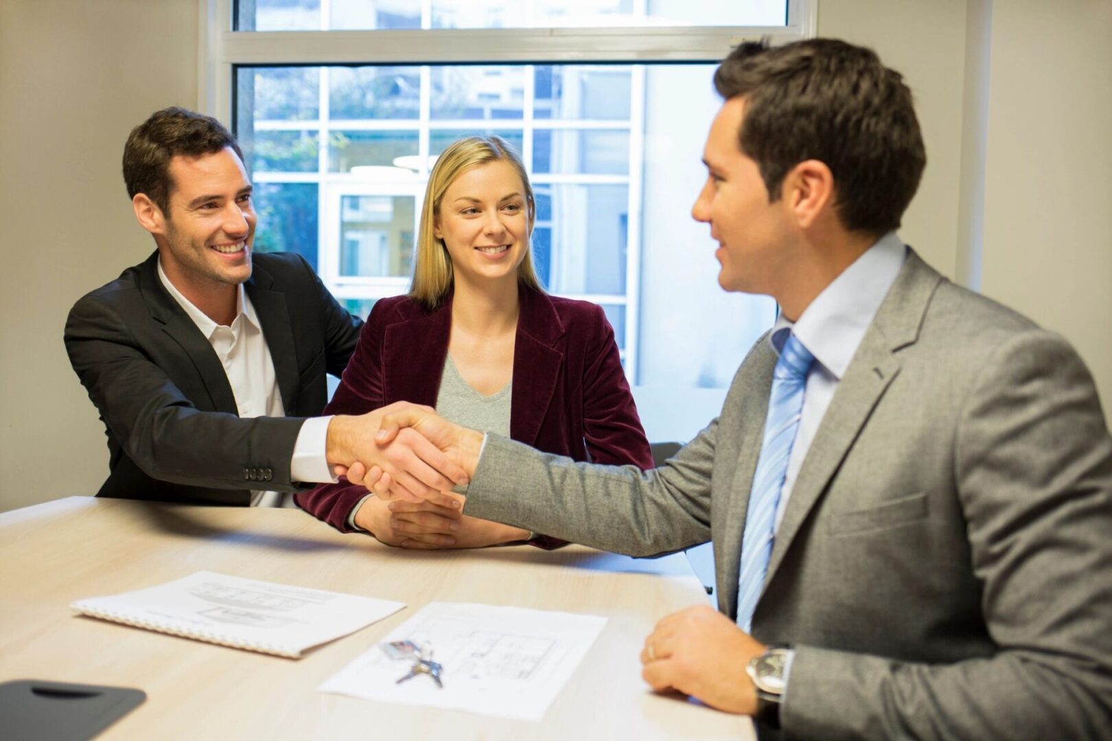 A group of people sitting at a table shaking hands.