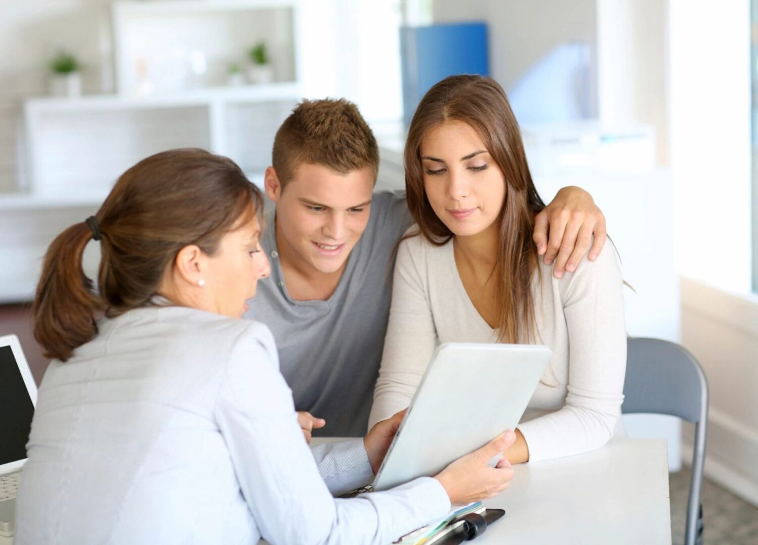 A group of people sitting around a table looking at something on the computer.